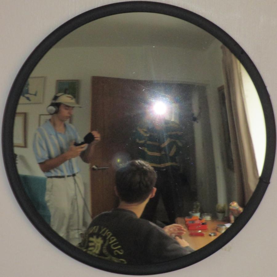 A mirror photo of the band recording, a camera flash covers one member’s face